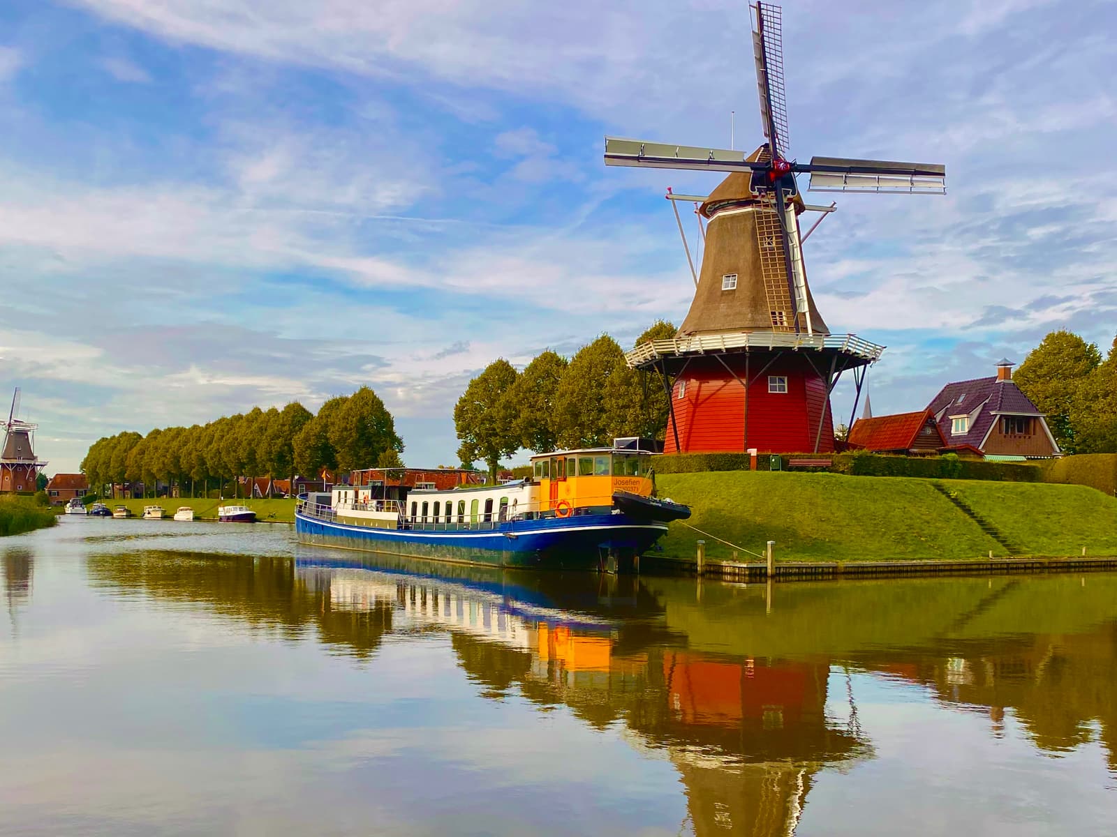 Ship Josefien moored beneath a windmill on the Eleven Cities route in Friesland