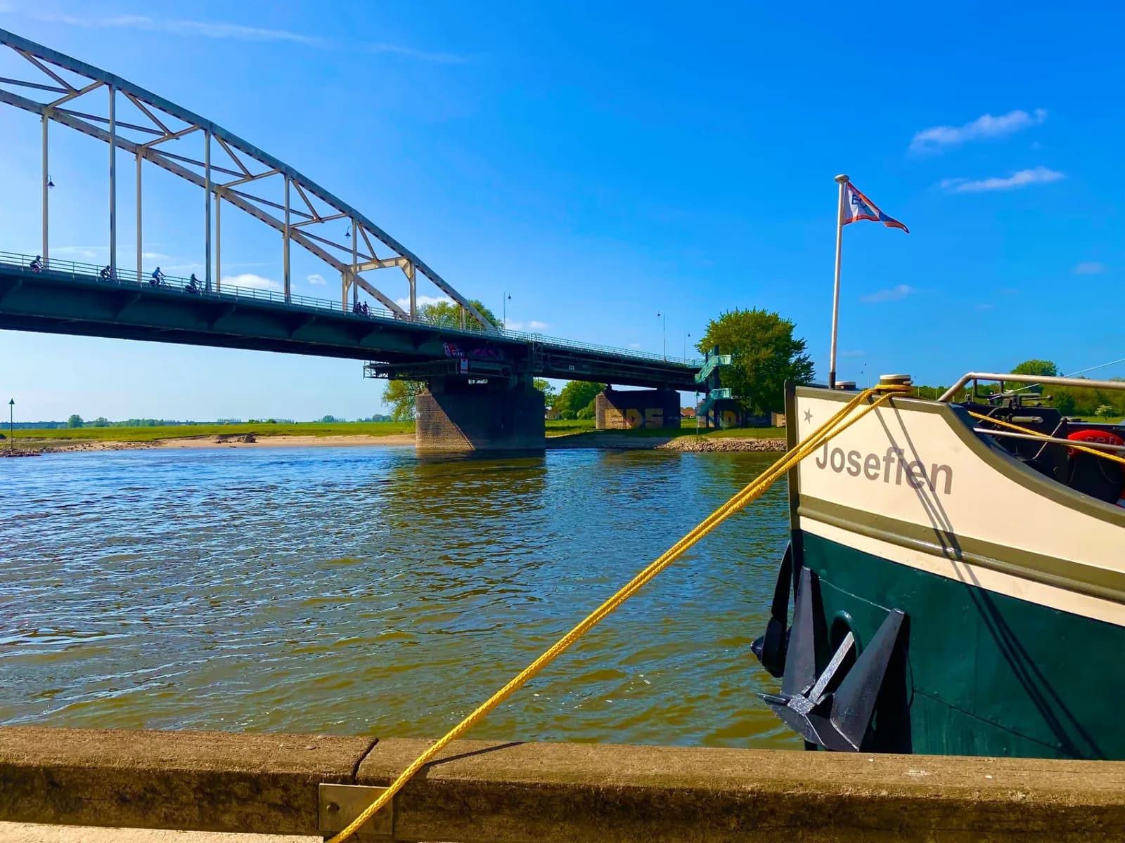 Bow of Ship Josefien moored on the river beside an arch bridge on the Hanseatic Route