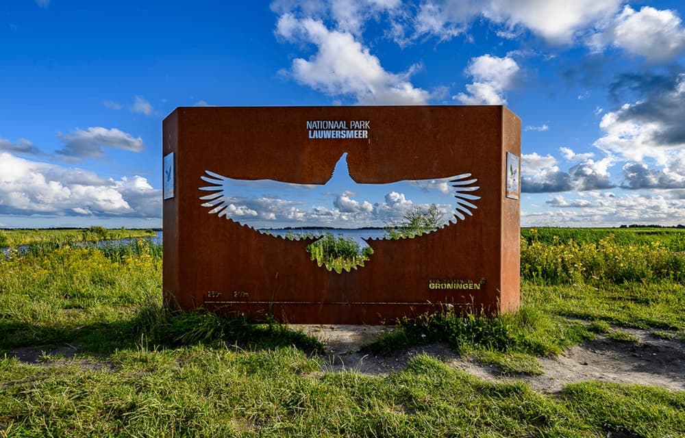 Steel sign of Lauwersmeer National Park with a bird cut-out, overlooking the lake
