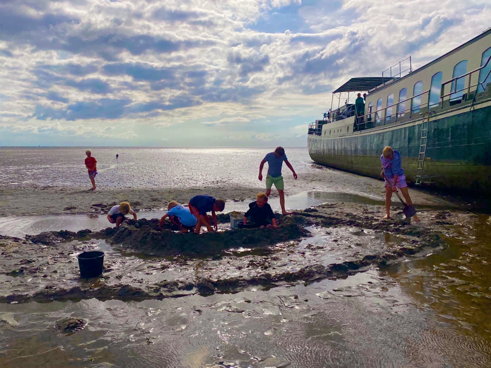 Ship Josefien dried out on a Wadden Sea sandbank while guests dig in the sand beside her